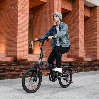 Rider cycling on the ADO Air 20 Pro in grey past a brick building